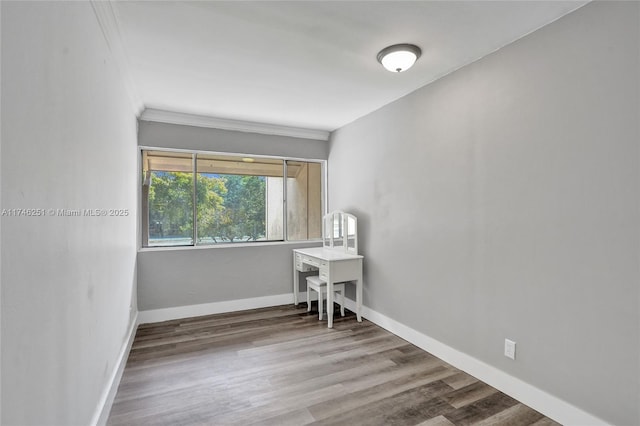 empty room featuring wood-type flooring and crown molding