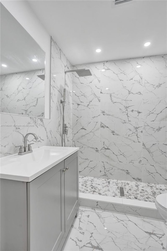 bathroom featuring vanity, toilet, and a tile shower