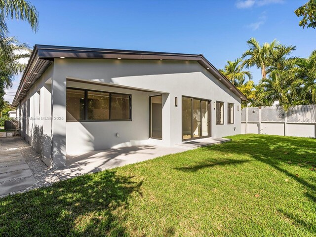 view of front facade with fence, a front lawn, and stucco siding