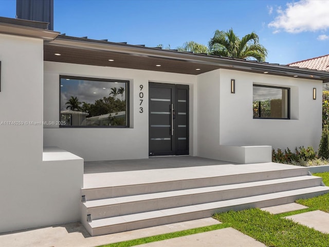 view of exterior entry featuring a porch and stucco siding