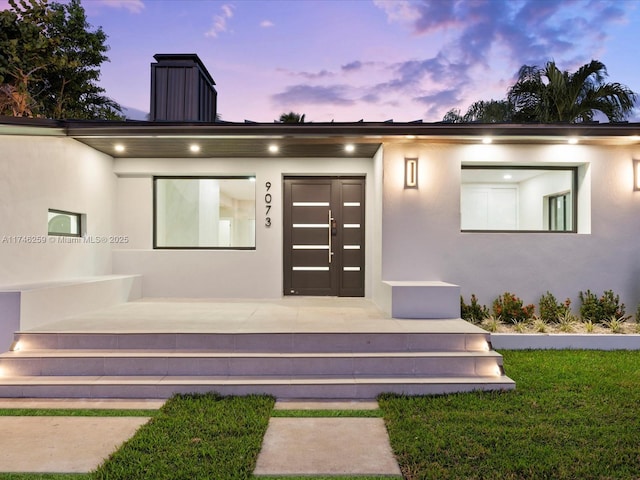 entrance to property with a chimney and stucco siding