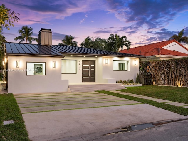 exterior space with a standing seam roof, metal roof, a chimney, and stucco siding