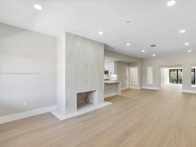 unfurnished living room featuring light wood-type flooring, baseboards, visible vents, and recessed lighting