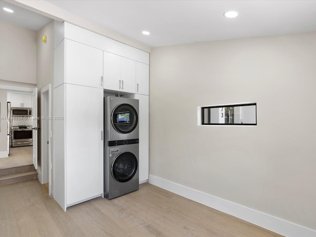 laundry room with recessed lighting, light wood-style flooring, stacked washer / dryer, laundry area, and baseboards