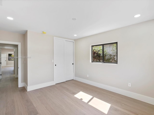 unfurnished bedroom featuring light wood-type flooring, recessed lighting, a closet, and baseboards