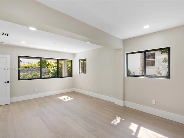 spare room with baseboards, visible vents, and wood finished floors