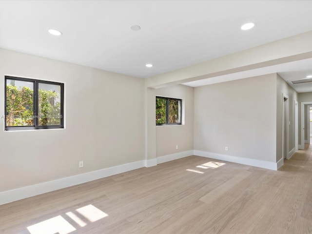 spare room featuring light wood-type flooring, baseboards, and recessed lighting