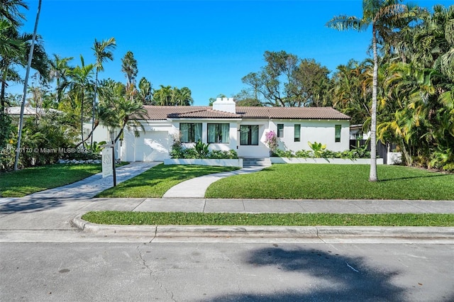 view of front of property featuring stucco siding, driveway, a tile roof, an attached garage, and a front yard