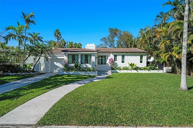 view of front of home featuring a front lawn, a tile roof, stucco siding, a chimney, and an attached garage