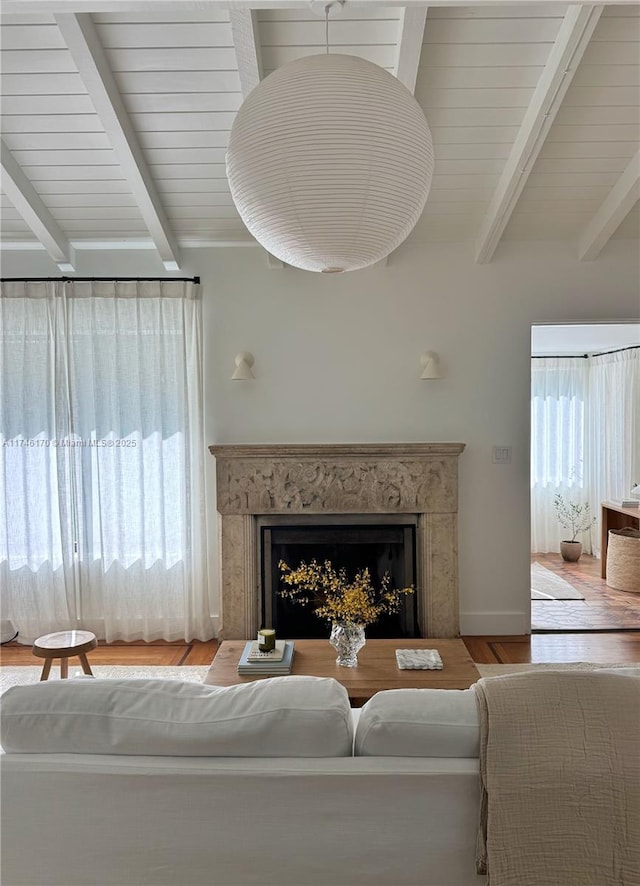 living room featuring vaulted ceiling with beams, wooden ceiling, a premium fireplace, and light wood-type flooring