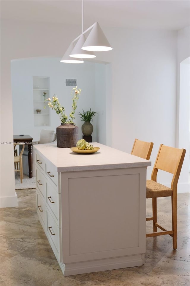 interior space with white cabinetry, a center island, light hardwood / wood-style floors, a kitchen bar, and decorative light fixtures