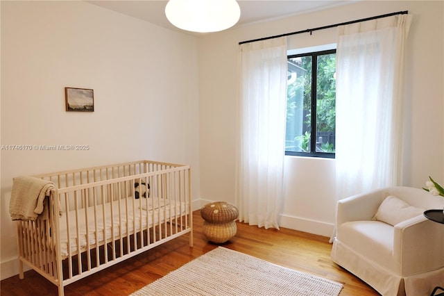 bedroom with a crib and wood-type flooring