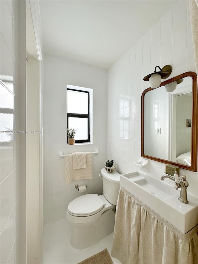 bathroom featuring tile patterned flooring, sink, tile walls, and toilet