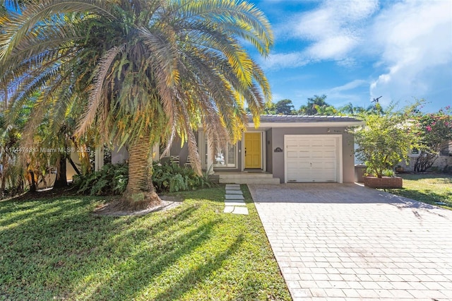 view of property hidden behind natural elements with a garage, a front yard, decorative driveway, and stucco siding