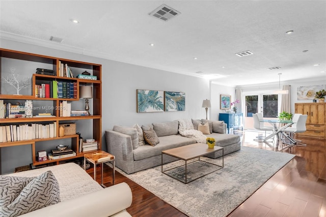 living room featuring dark wood finished floors, visible vents, crown molding, and a textured ceiling