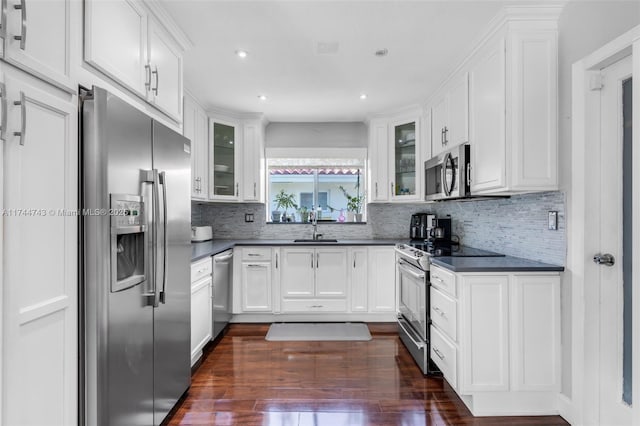 kitchen with appliances with stainless steel finishes, dark countertops, glass insert cabinets, and white cabinets