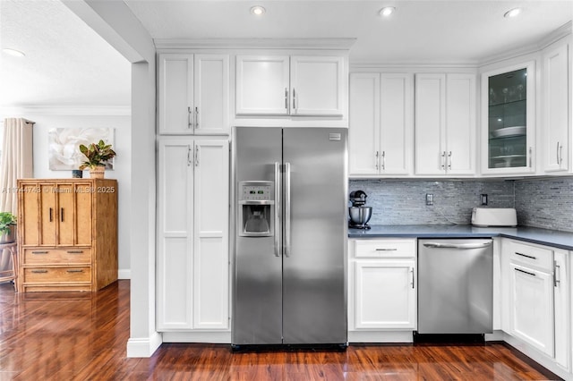 kitchen with dark countertops, white cabinetry, glass insert cabinets, and stainless steel appliances