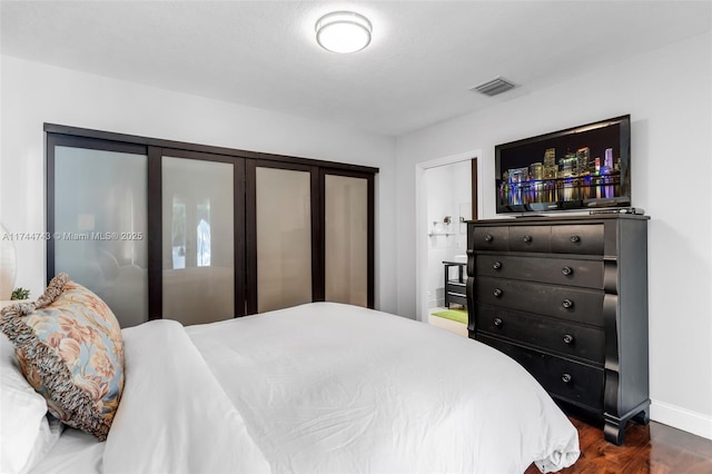 bedroom with dark wood-style flooring, visible vents, and baseboards