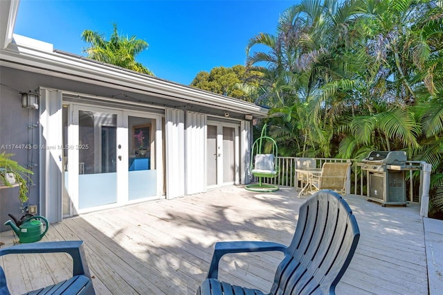 wooden deck with outdoor dining area, french doors, and grilling area