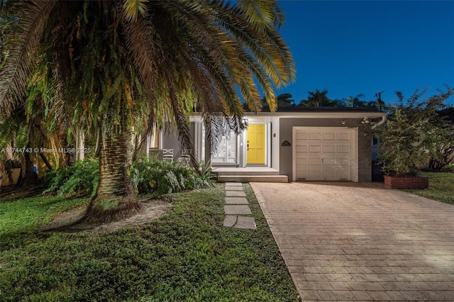 view of front of house with a garage, decorative driveway, and stucco siding