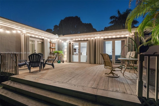 deck at night with french doors and outdoor dining area