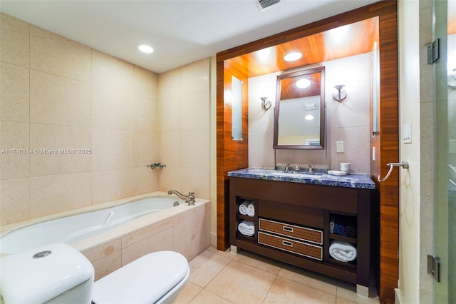 bathroom with toilet, tile walls, vanity, tiled tub, and tile patterned flooring