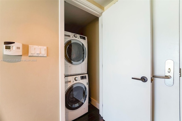 clothes washing area featuring stacked washer and dryer and dark wood-type flooring