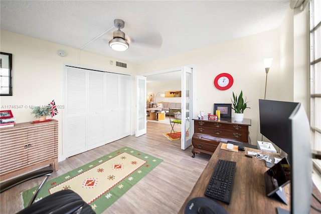 interior space featuring visible vents, ceiling fan, a textured ceiling, and wood finished floors