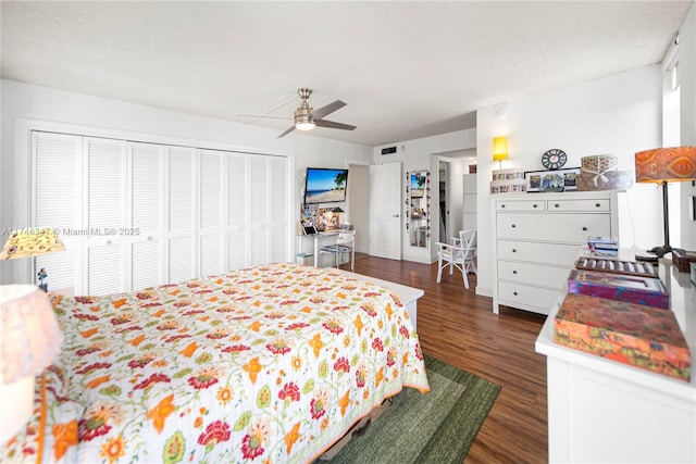 bedroom featuring a textured ceiling, dark wood-style flooring, visible vents, a ceiling fan, and a closet