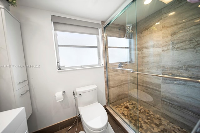 bathroom with a stall shower, baseboards, and toilet