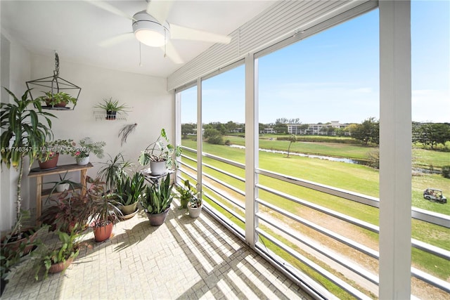 sunroom featuring a water view and a ceiling fan