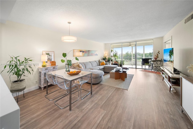 living area with expansive windows, a textured ceiling, baseboards, and wood finished floors