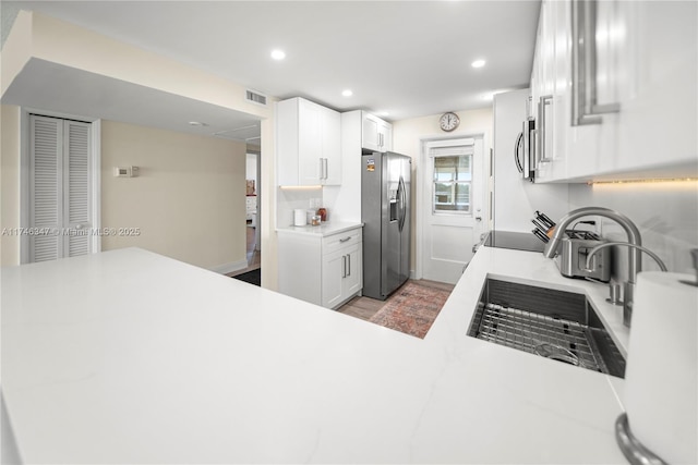 kitchen featuring light countertops, stainless steel fridge, recessed lighting, and white cabinetry