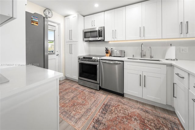 kitchen featuring stainless steel appliances, light wood-style floors, light countertops, and a sink