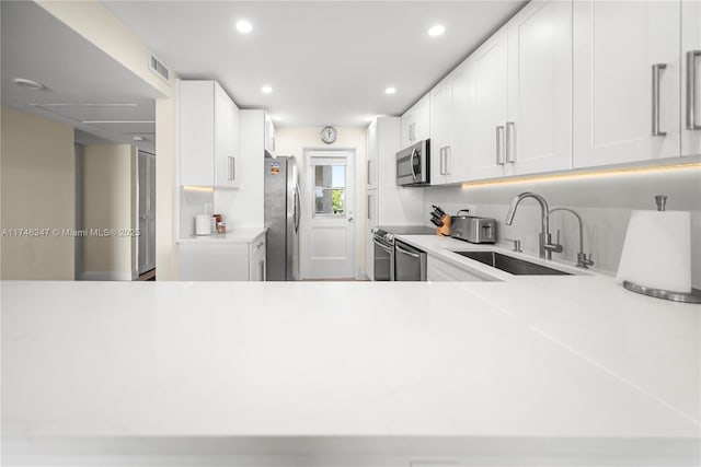 kitchen with visible vents, stainless steel appliances, a sink, and light countertops