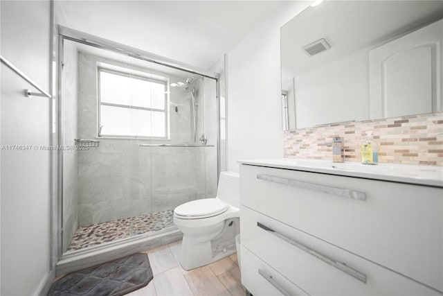 bathroom featuring visible vents, backsplash, toilet, a shower stall, and vanity