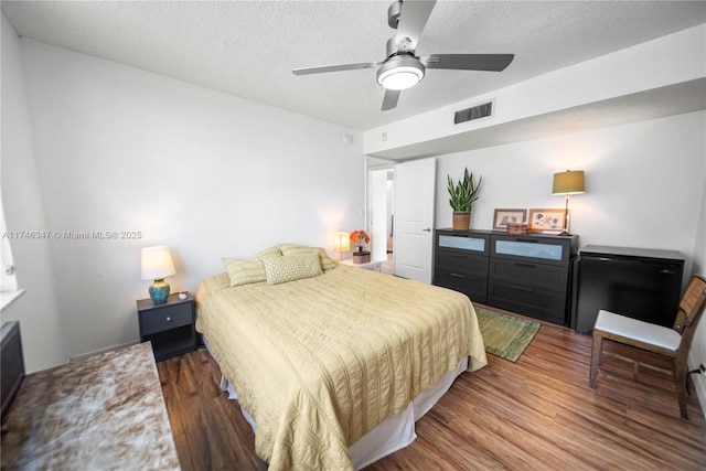 bedroom featuring a textured ceiling, ceiling fan, wood finished floors, and visible vents