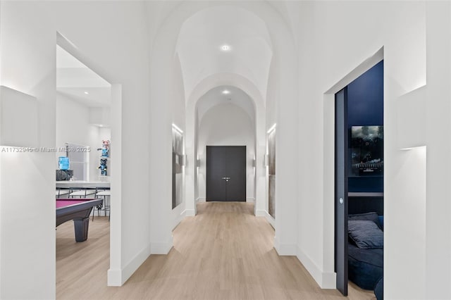 hall featuring light hardwood / wood-style flooring and a high ceiling