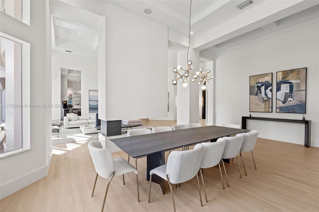 dining space featuring a high ceiling, a notable chandelier, and light hardwood / wood-style floors