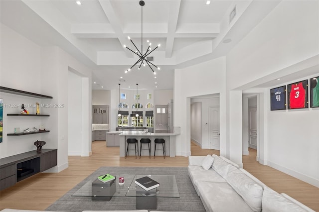 living room featuring beam ceiling, coffered ceiling, a towering ceiling, and light wood-type flooring