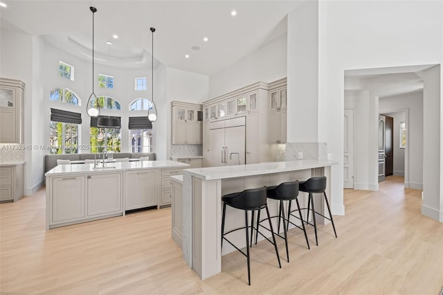 kitchen featuring pendant lighting, a kitchen island with sink, a kitchen breakfast bar, paneled refrigerator, and kitchen peninsula