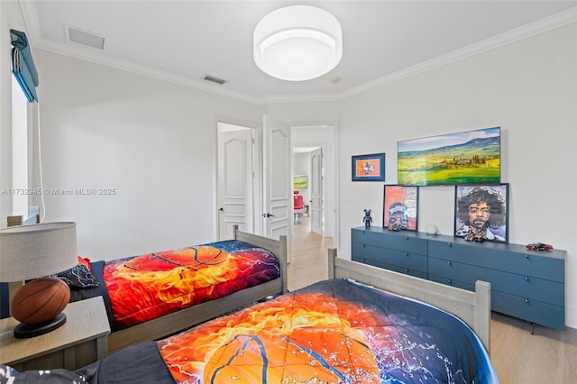 bedroom with ornamental molding and light hardwood / wood-style flooring