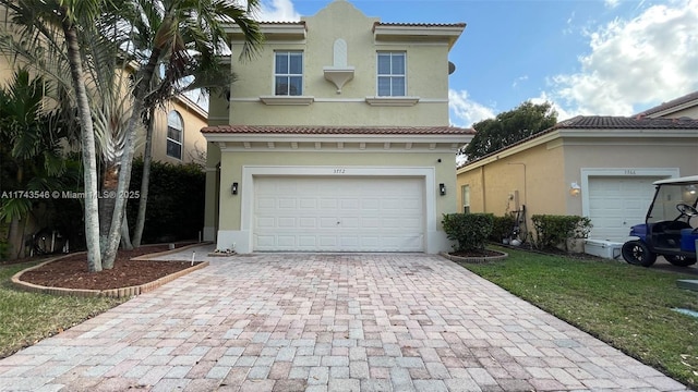 view of front of property featuring stucco siding, decorative driveway, an attached garage, and a tiled roof