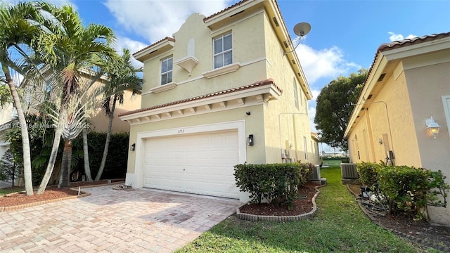 view of front of home with an attached garage, central AC, and stucco siding