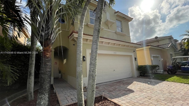 view of front of property with stucco siding, decorative driveway, and an attached garage