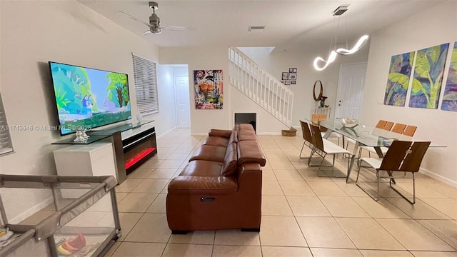 living room with visible vents, a ceiling fan, light tile patterned floors, baseboards, and stairs