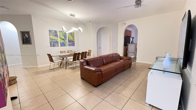 living room with visible vents, arched walkways, light tile patterned floors, baseboards, and ceiling fan