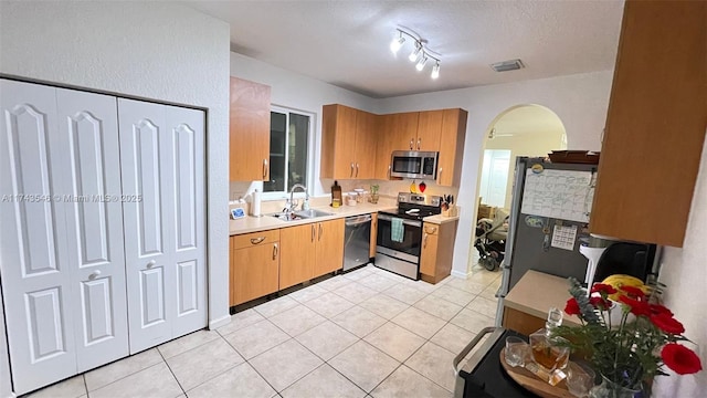 kitchen featuring visible vents, light countertops, arched walkways, stainless steel appliances, and a sink