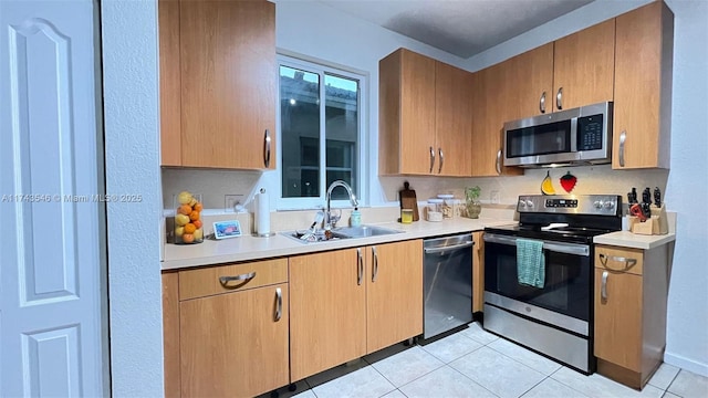 kitchen featuring a sink, stainless steel appliances, light countertops, and light tile patterned floors