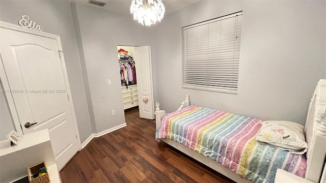 bedroom featuring wood finished floors, visible vents, a spacious closet, a closet, and a chandelier